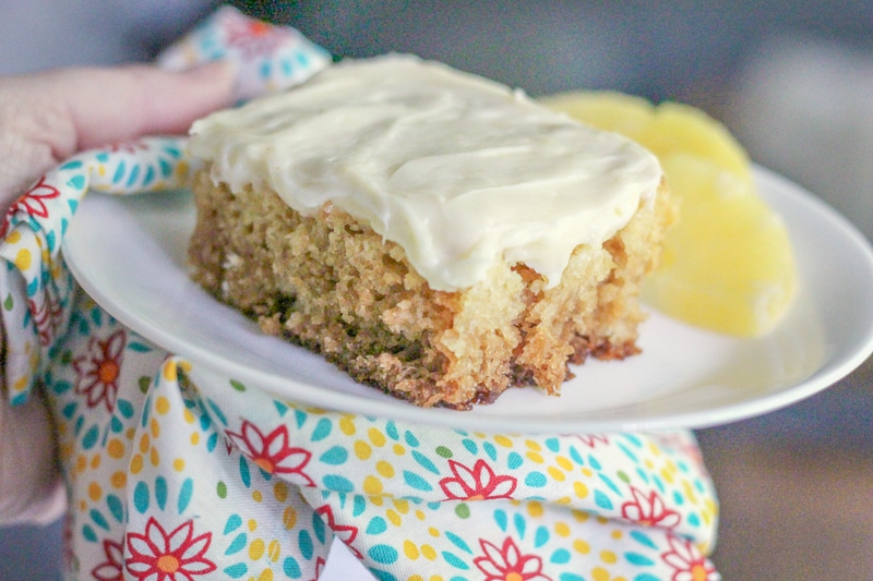 hand holding a plate with crushed pineapple cake