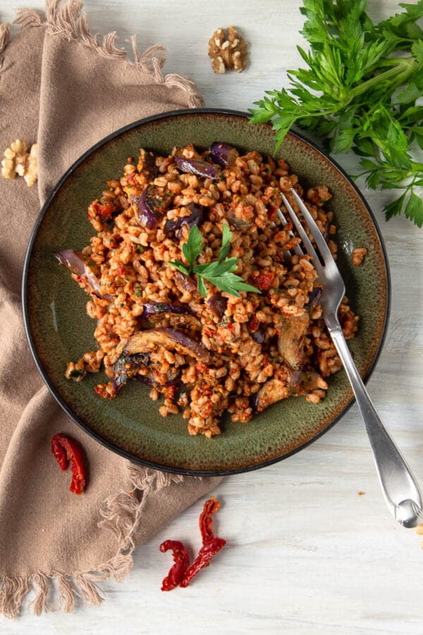 farro salad on a green plate with a fork and a cloth napkin