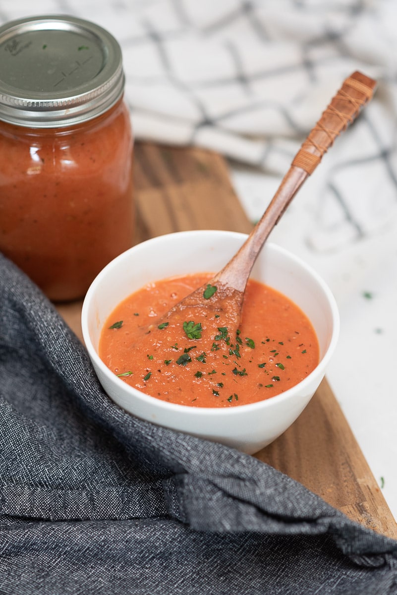 bowl of homemade marinara sauce with a jar in the background