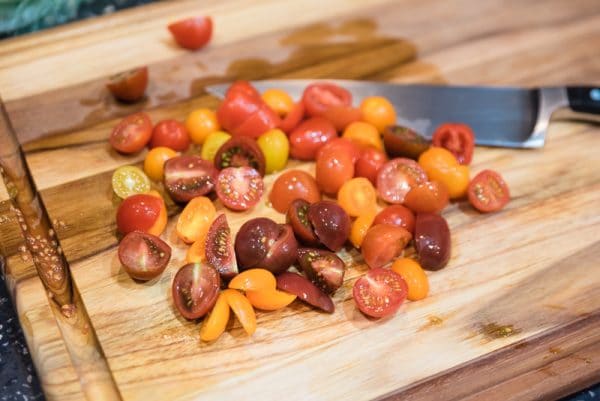 chopping cherry tomatoes on a cutting board