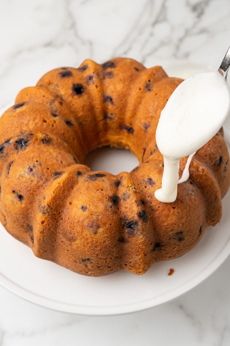 lemon blueberry bundt cake being drizzled with glaze