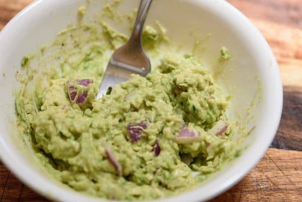 mashing homemade guacamole for nachos