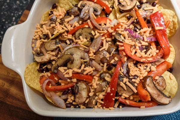 layering vegan nachos in baking dish