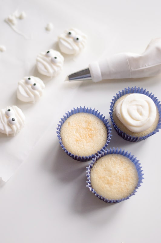 putting icing on mummy cupcakes