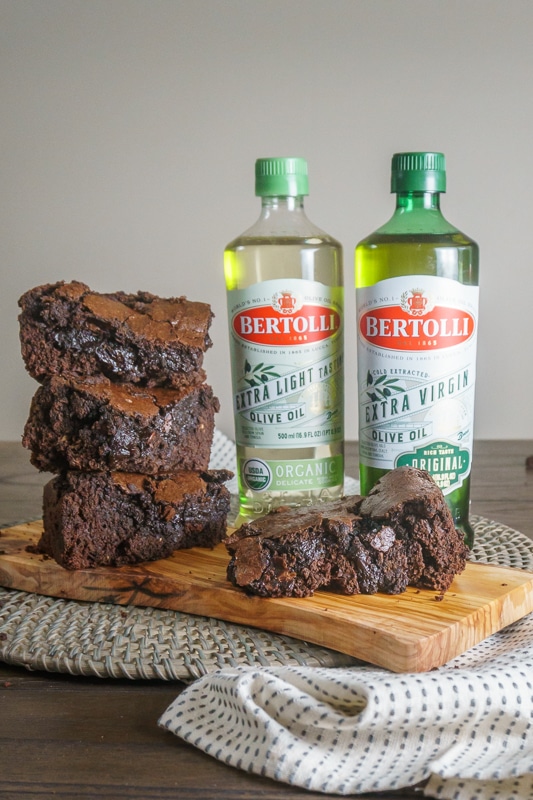 olive oil brownies stacked next to olive oil bottles