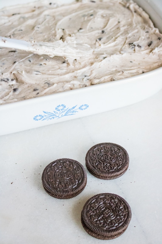 spreading frosting on the oreo poke cake