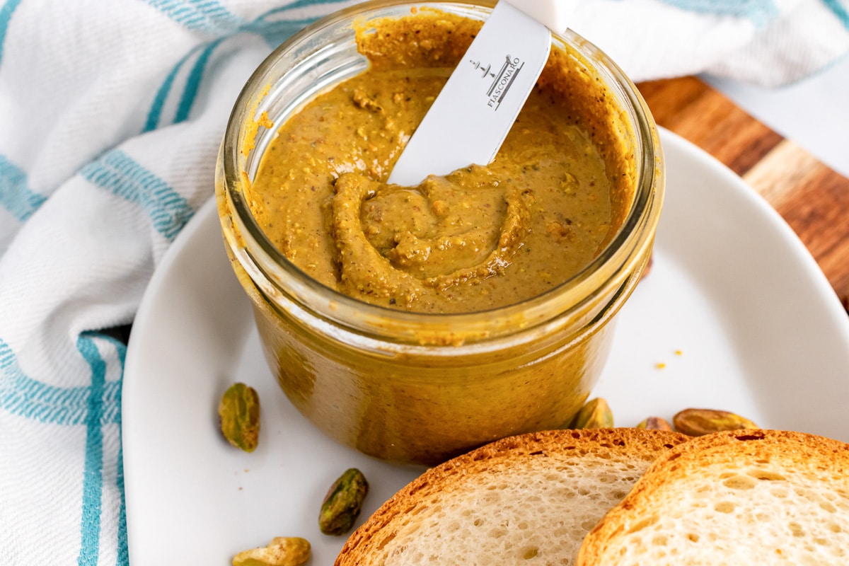 jar of pistachio butter on plate with bread slices