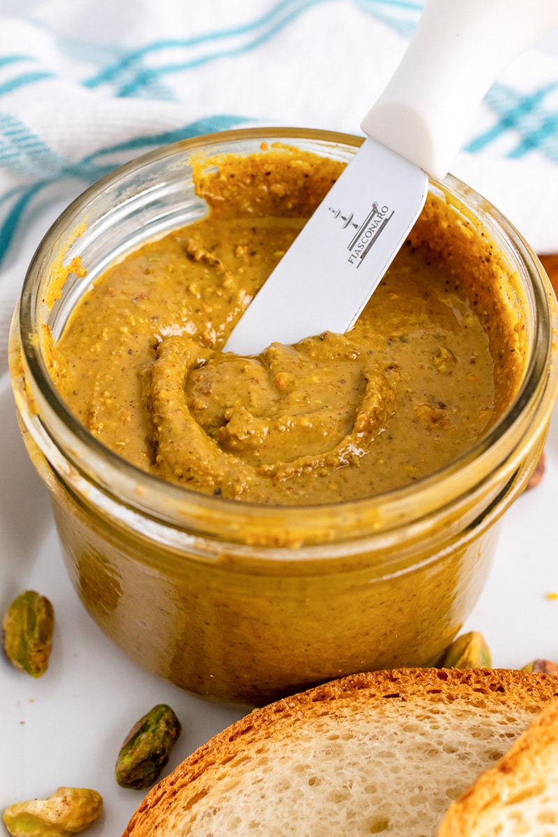 dipping knife into jar of pistachio butter