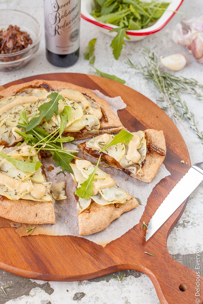 Nutty spelt makes a perfect base for this caramelised onion and vegan potato pizza recipe. Topped with balsamic garlic cashew aioli and a few rocket (arugula) leaves its the perfect thing to serve to friends over a few drinks. | Get the recipe at deliciouseveryday.com