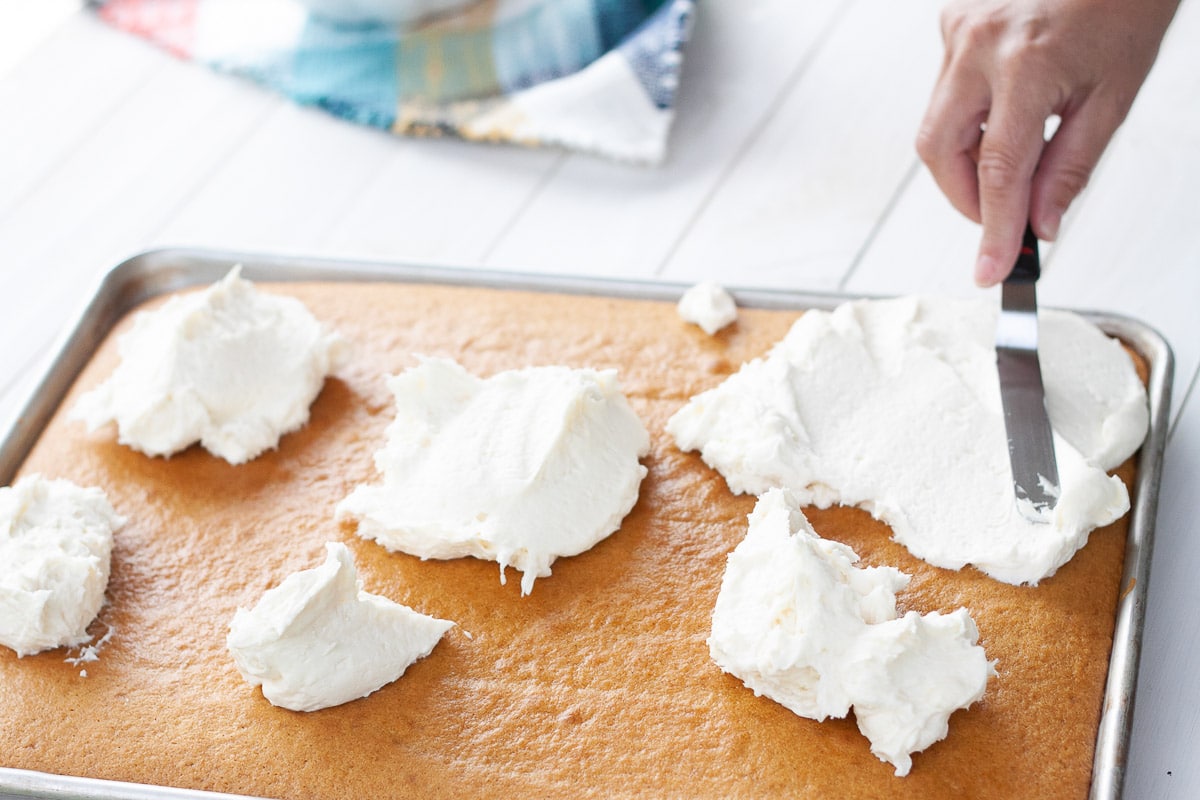 spreading the vegan cream cheese frosting onto tray of vegan pumpkin bars