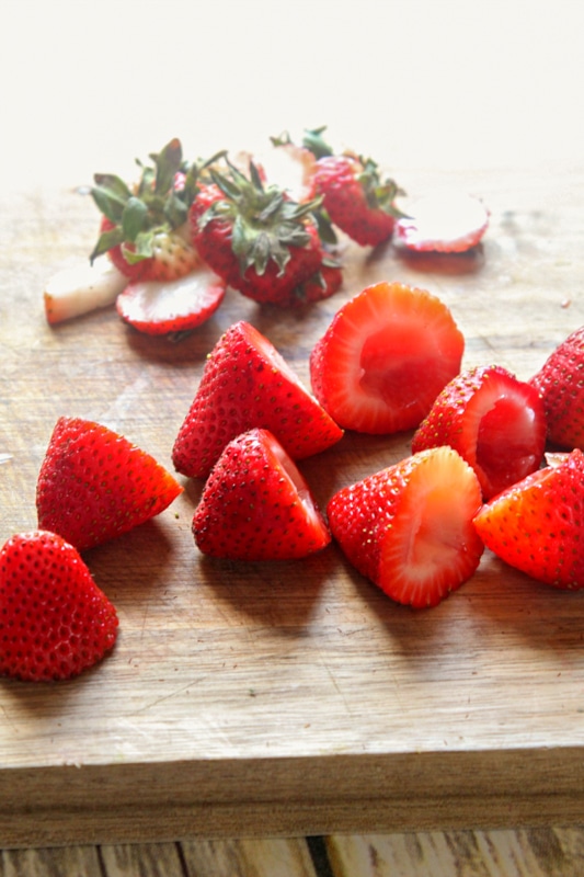 strawberries on a cutting board with stems removed