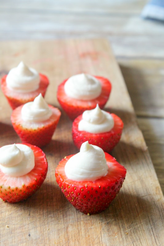 cheesecake stuffed strawberries on a cutting board