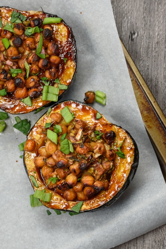 vegan stuffed acorn squash being served on a baking sheet