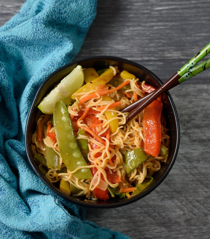 vegetarian thai noodles in red curry sauce in a black bowl