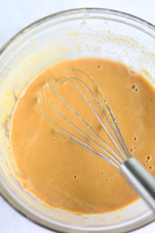 smooth and velvety thai peanut sauce being stirred in a big glass bowl