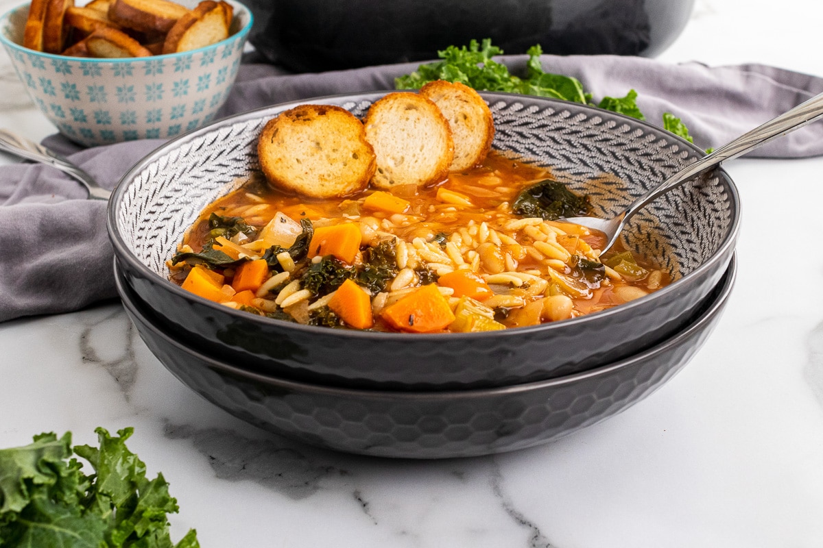 two stacked bowls with tuscan kale soup and spoon in top bowl