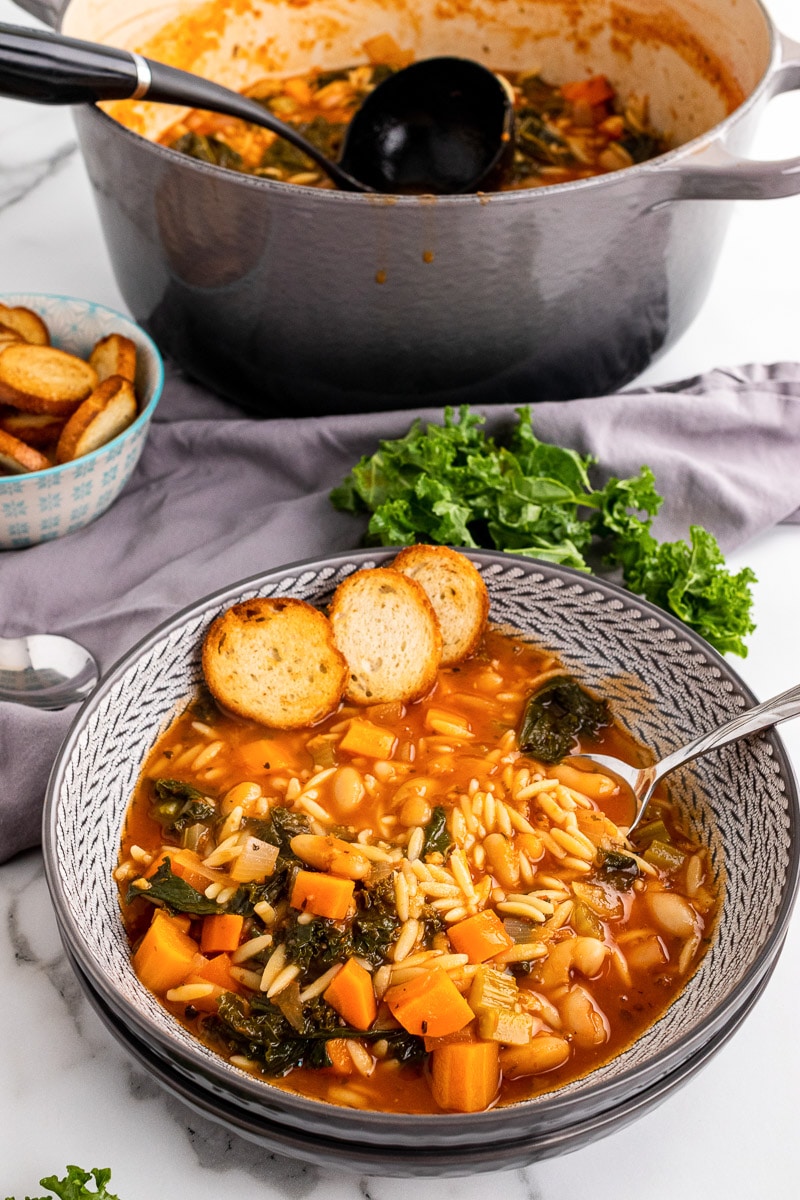 bowl of tuscan kale soup in front of pot of soup