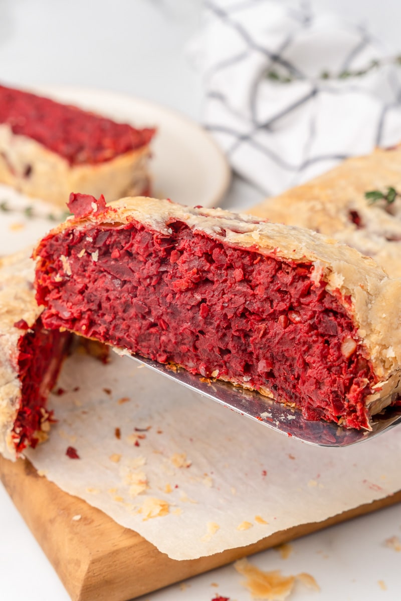lifting up a slice of vegan beet wellington with a fork