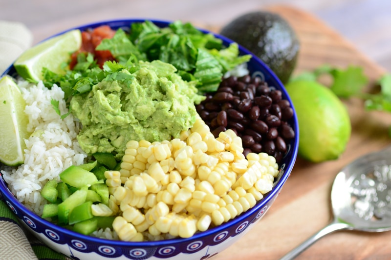 vegan burrito bowl topped with guacamole and fresh veggies