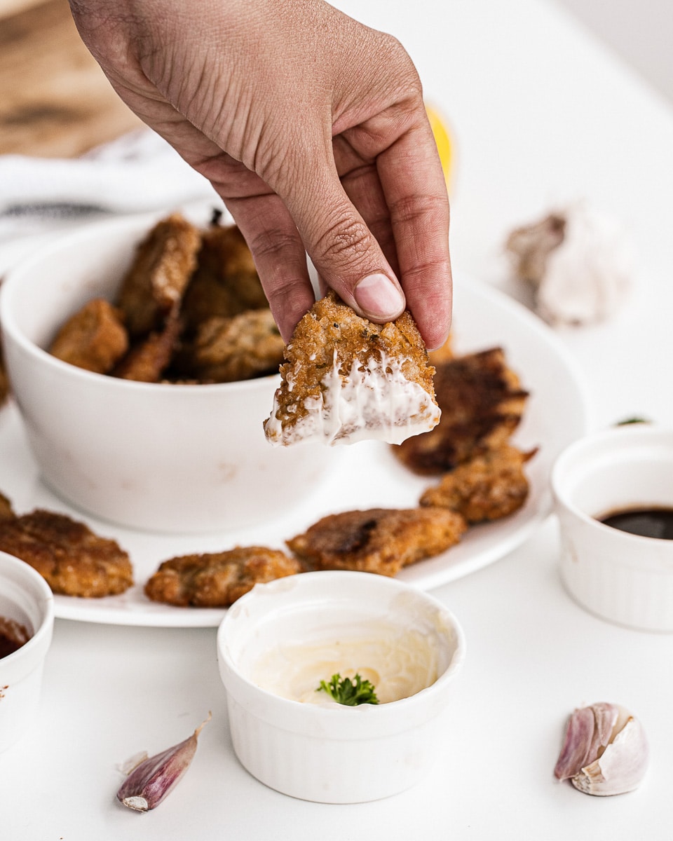 dipping cauliflower nuggets into sauce