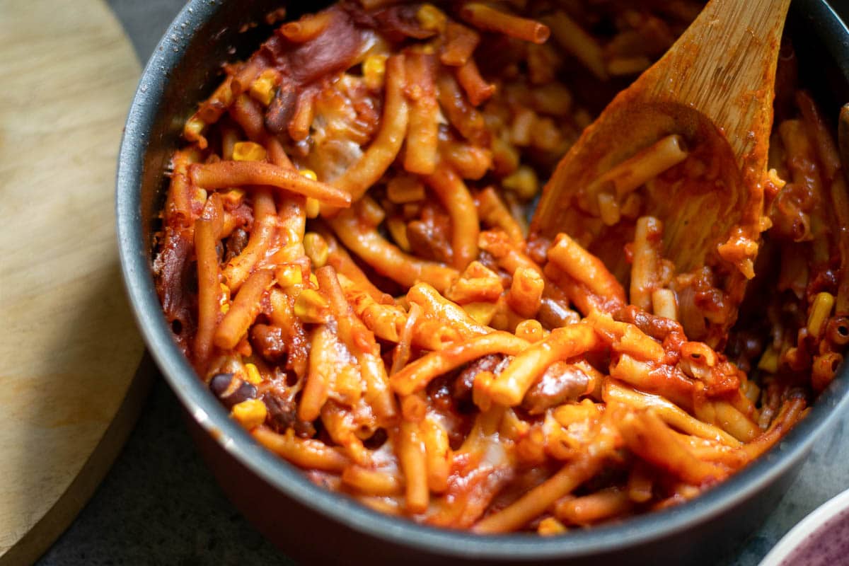 vegan chili mac in a bowl with wooden spoon