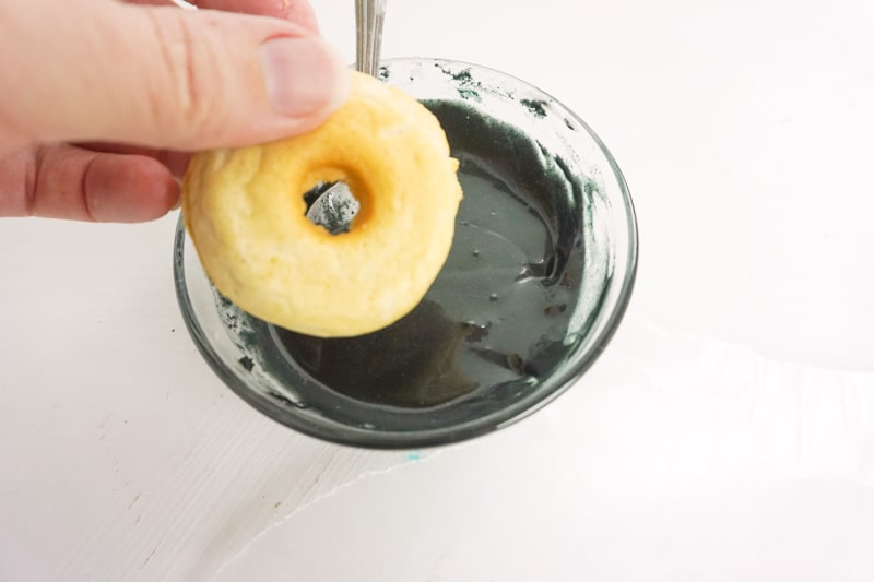 dipping each donut into the vegan chocolate glaze