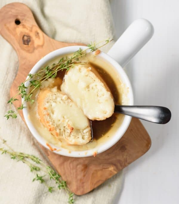 vegan french onion soup being served in a white bowl