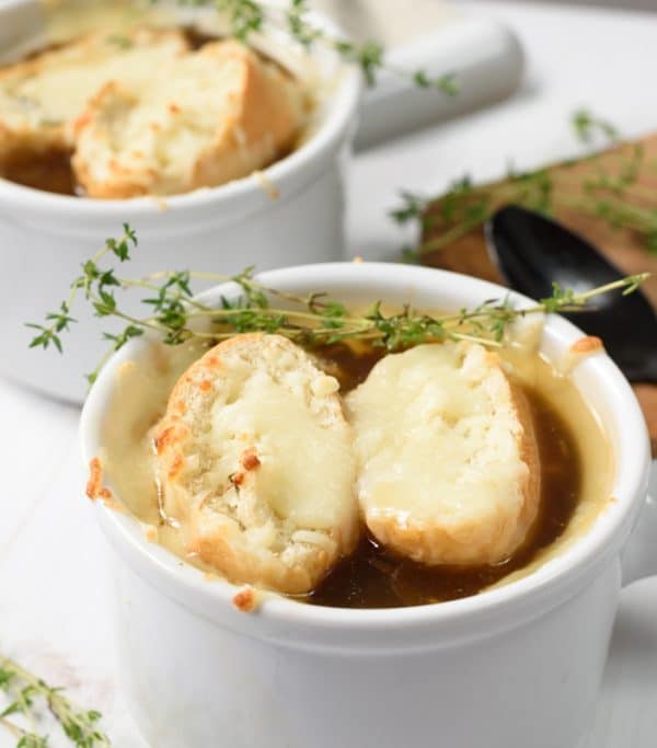 closeup of vegan french onion soup topped with toasted baguette and melted vegan cheese