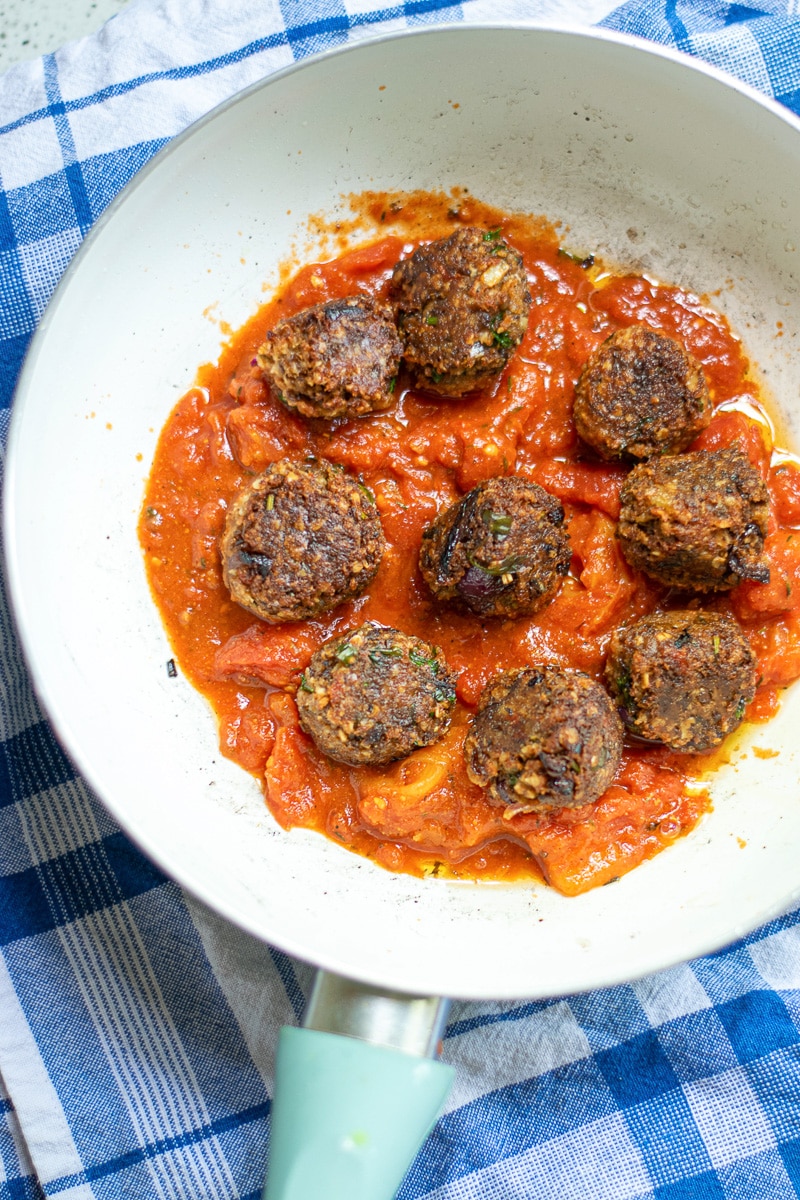 vegan lentil meatballs in marinara sauce, being served in a white bowl