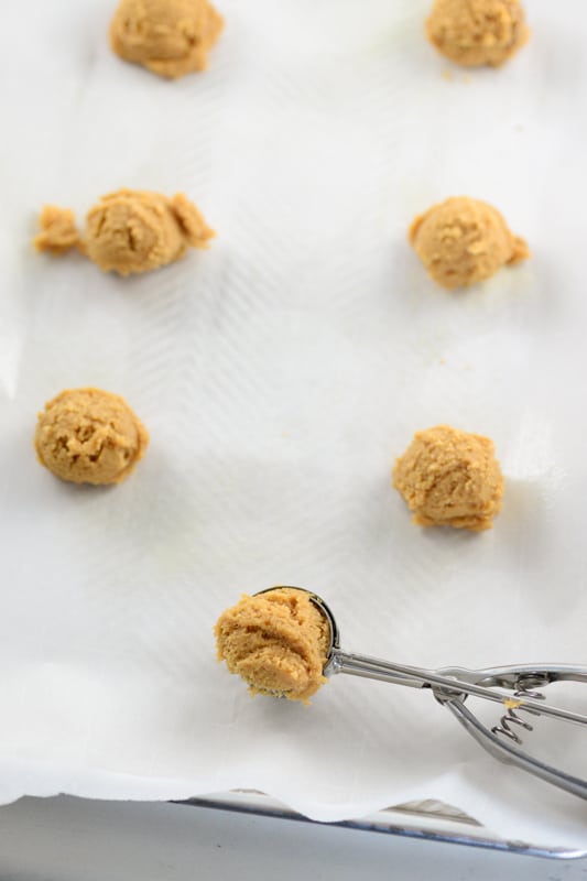 scooping vegan peanut butter cookie dough onto a baking sheet