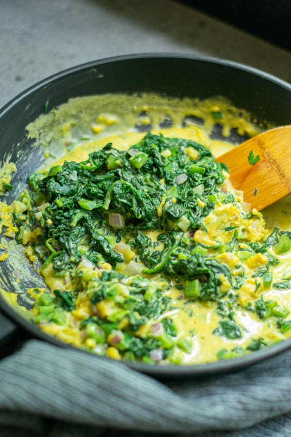 stirring the vegan scrambled eggs in a pan