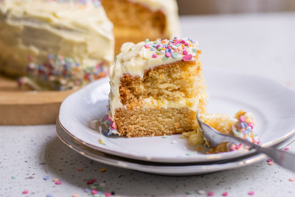 a slice of vegan vanilla cake being served on a plate
