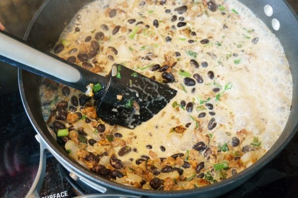 stirring vegetarian chili cheese dip on the stove