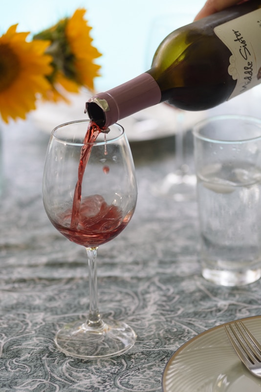 wine being poured in a glass by the pool