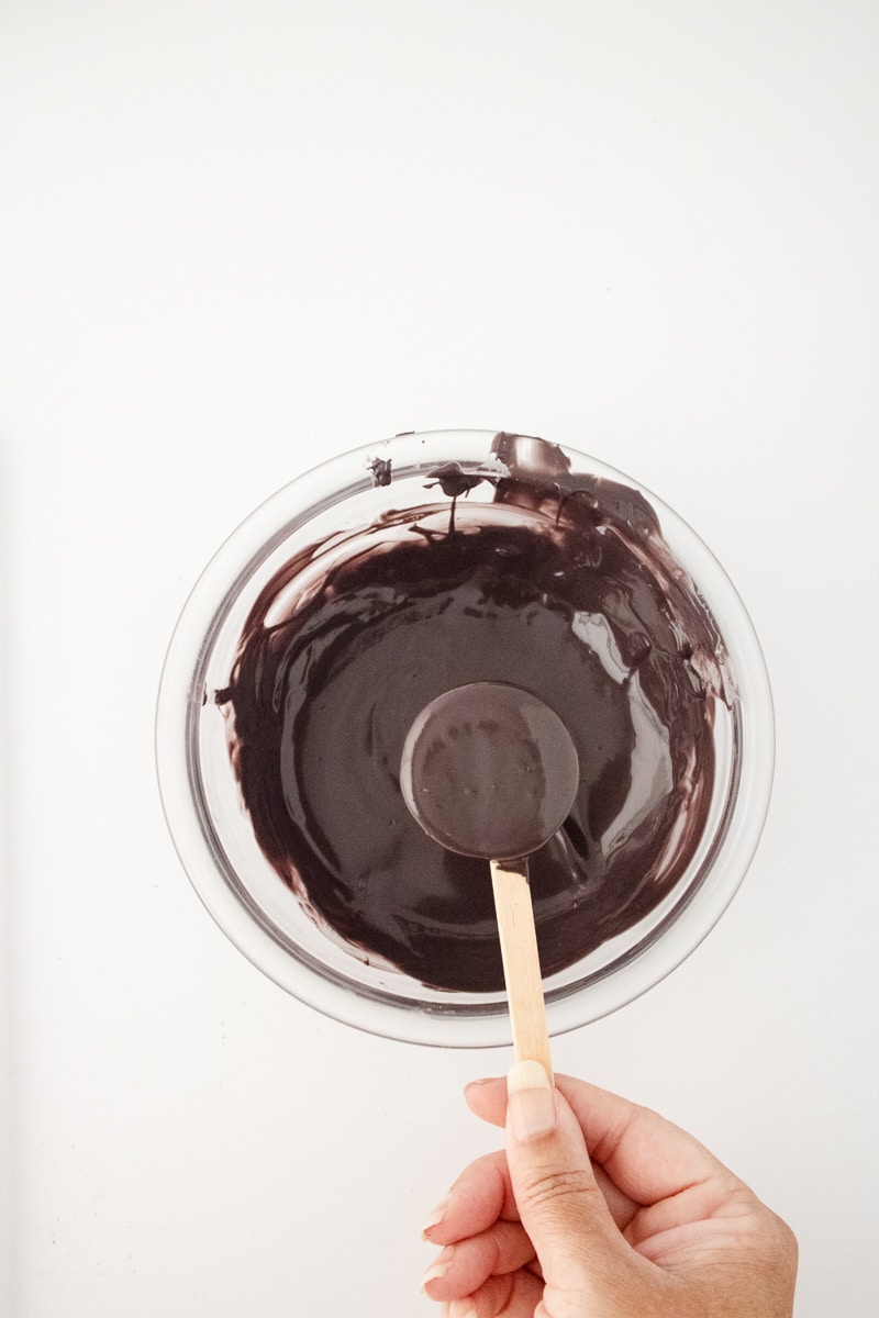 Dipping an Oreo pop into a bowl of melted black candy coating