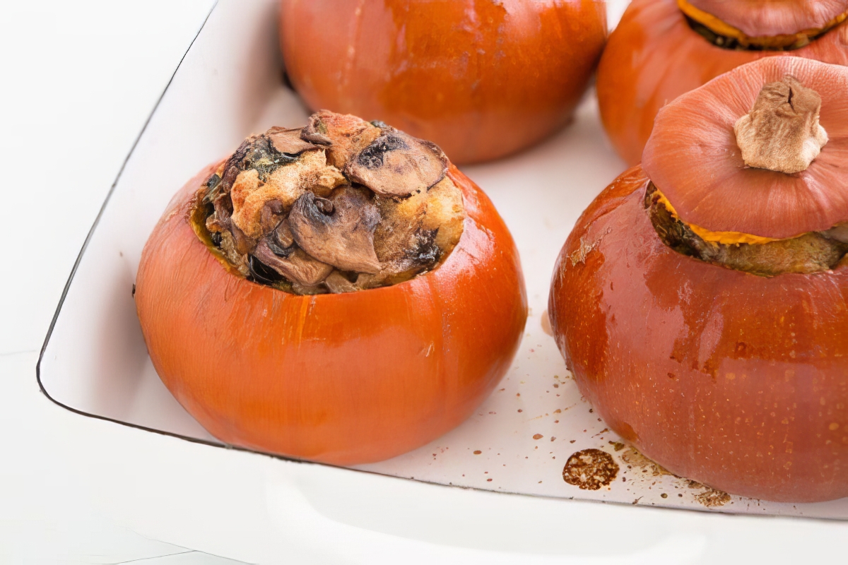 Vegetarian stuffed pumpkins with golden mushroom and bread filling in a white baking dish