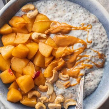 Apple pie coconut chia pudding topped with cinnamon apples, cashews, and peanut butter