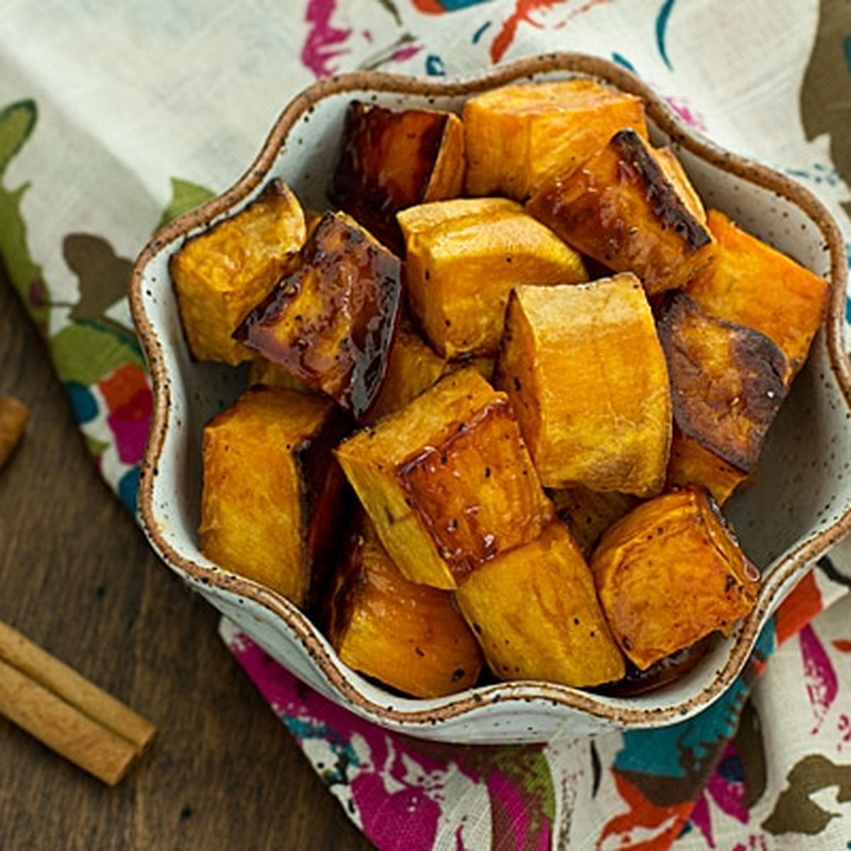 Bowl of apple cider glazed sweet potatoes with cinnamon sticks