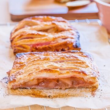 Golden puff pastry apple rhubarb pie with woven strips of pastry on top, cooling on a wire rack