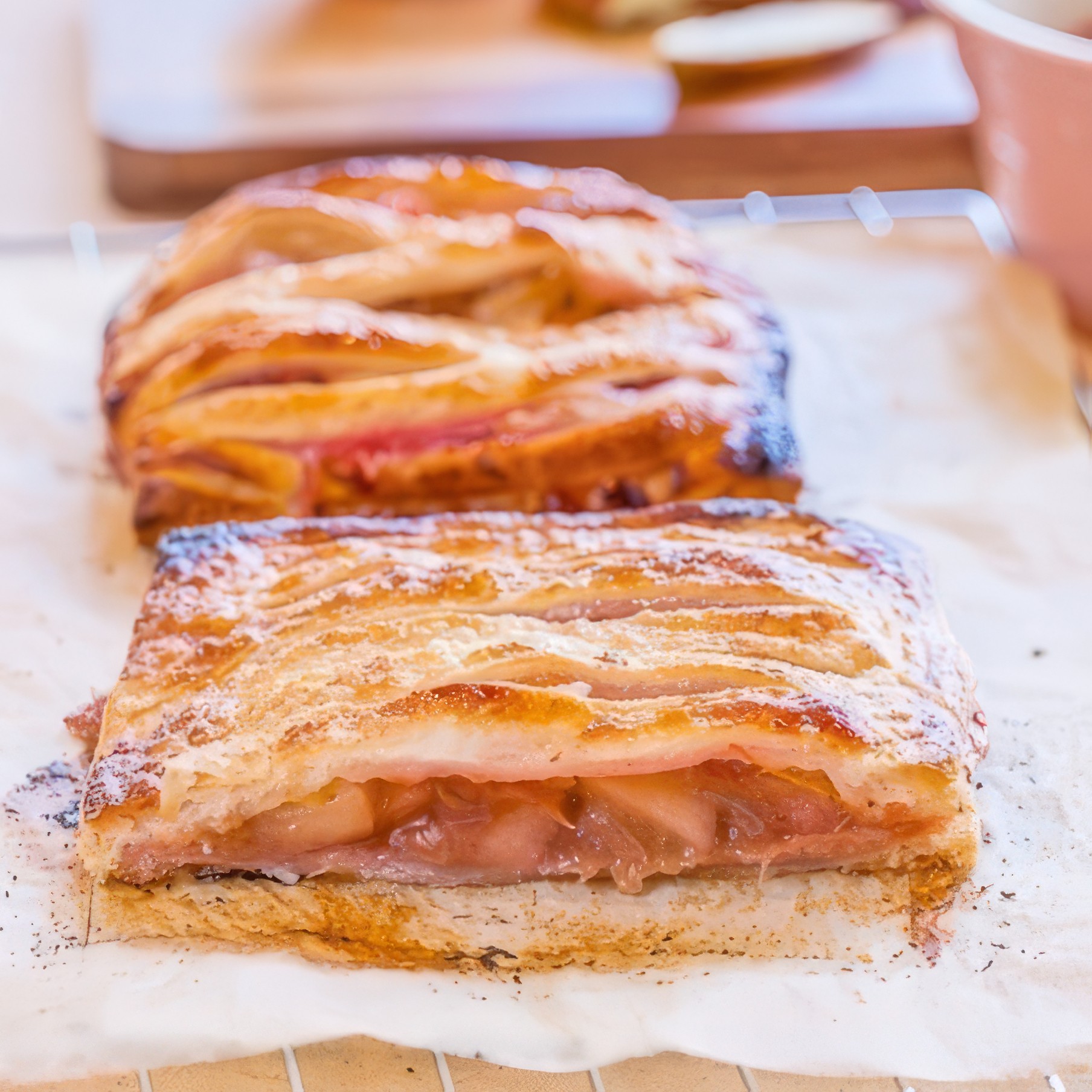 Golden puff pastry apple rhubarb pie with woven strips of pastry on top, cooling on a wire rack