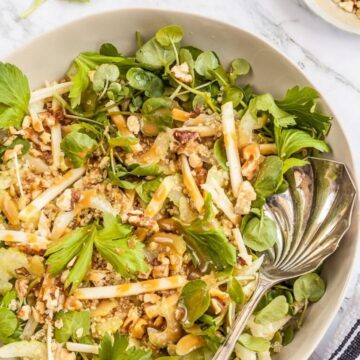 Overhead view of celery apple walnut salad with watercress and honey miso dressing in a bowl