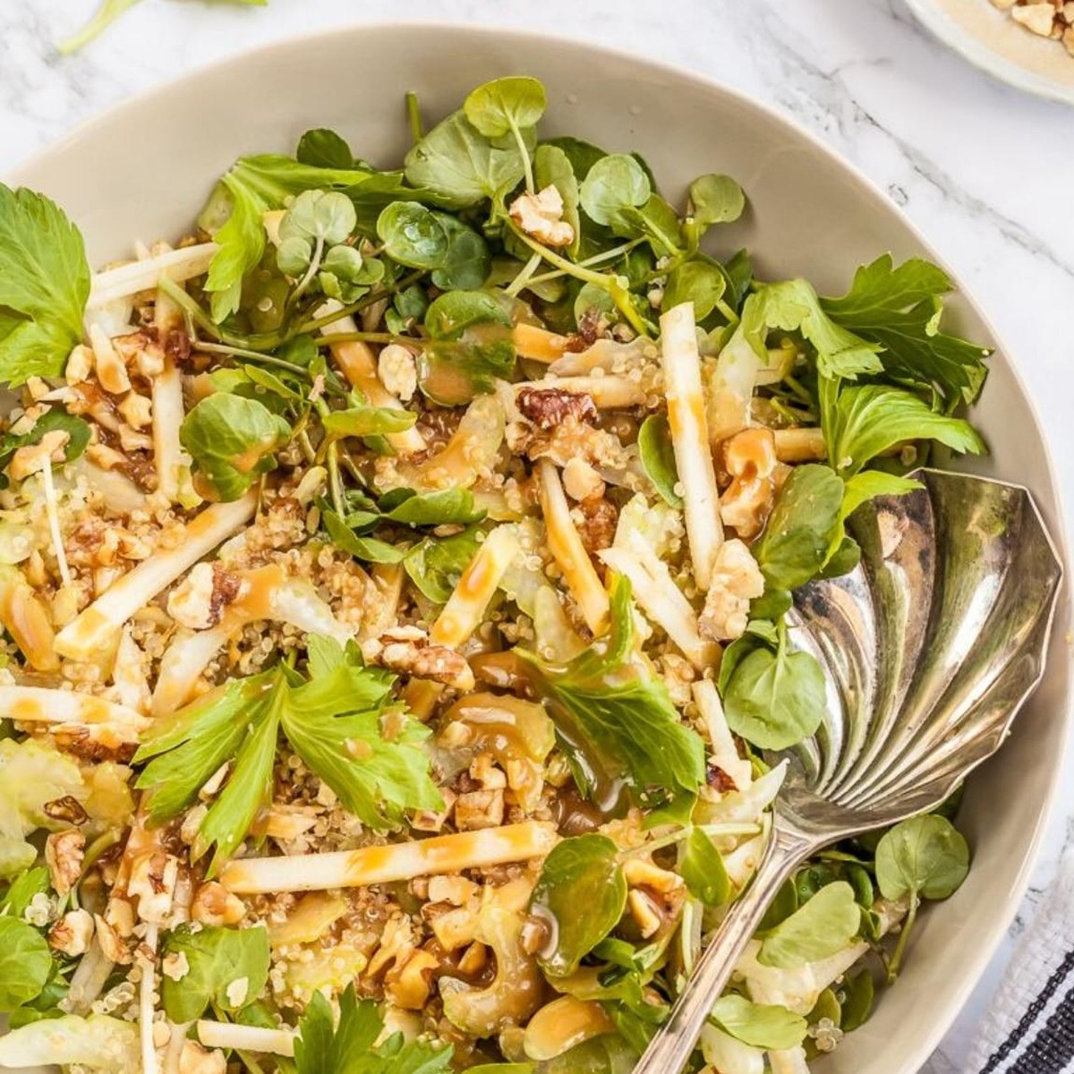 Overhead view of celery apple walnut salad with watercress and honey miso dressing in a bowl