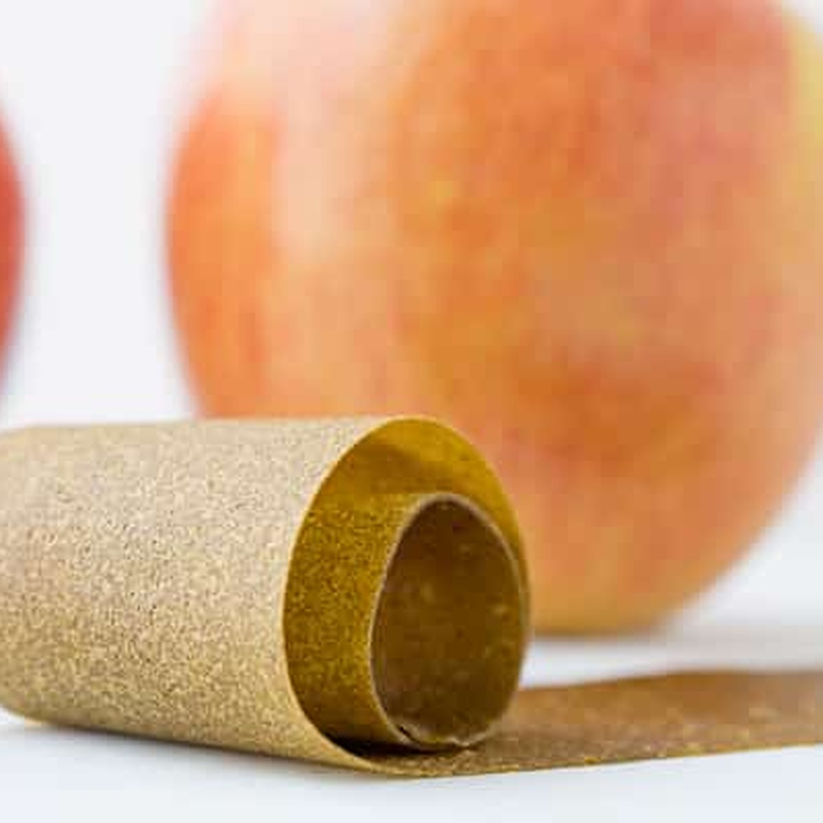 Rolled green apple fruit leather with fresh apples in the background