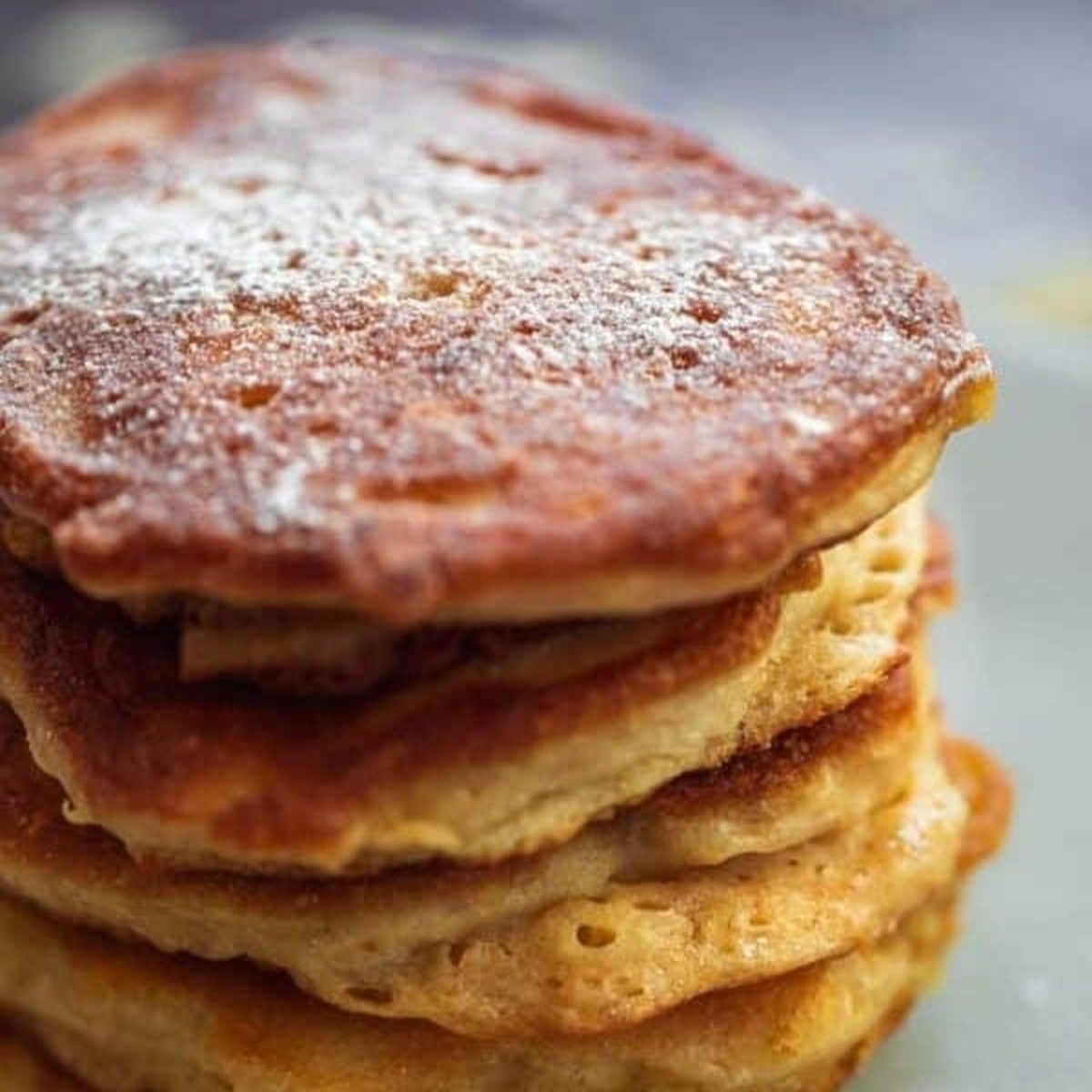 Stack of vegan apple pancakes (Oladyi) dusted with powdered sugar