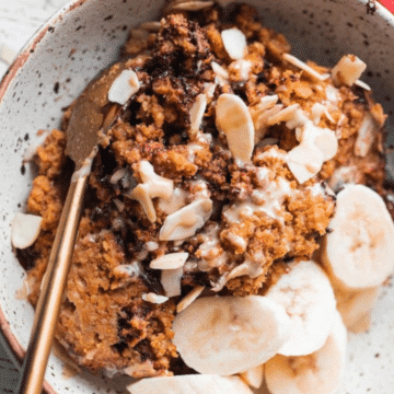 Vegan pumpkin baked oatmeal in a bowl with banana and sliced almonds