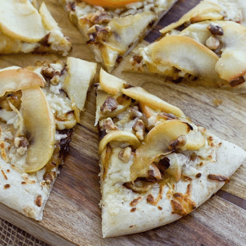 Apple cheddar pizza slices topped with sauteed apples, caramelized onions, cheddar and walnuts