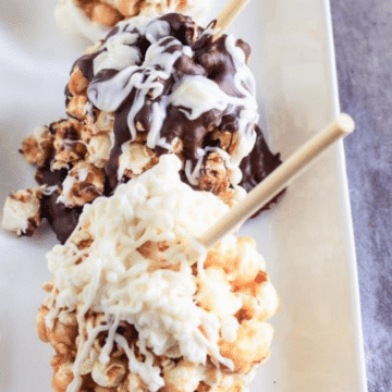 Caramel popcorn balls on sticks drizzled with white and milk chocolate