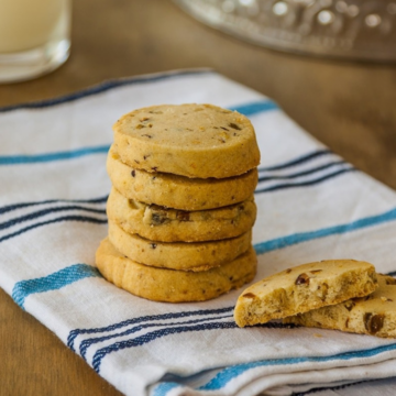 Cardamom cookies with lemon and pistachios stacked on a striped kitchen towel