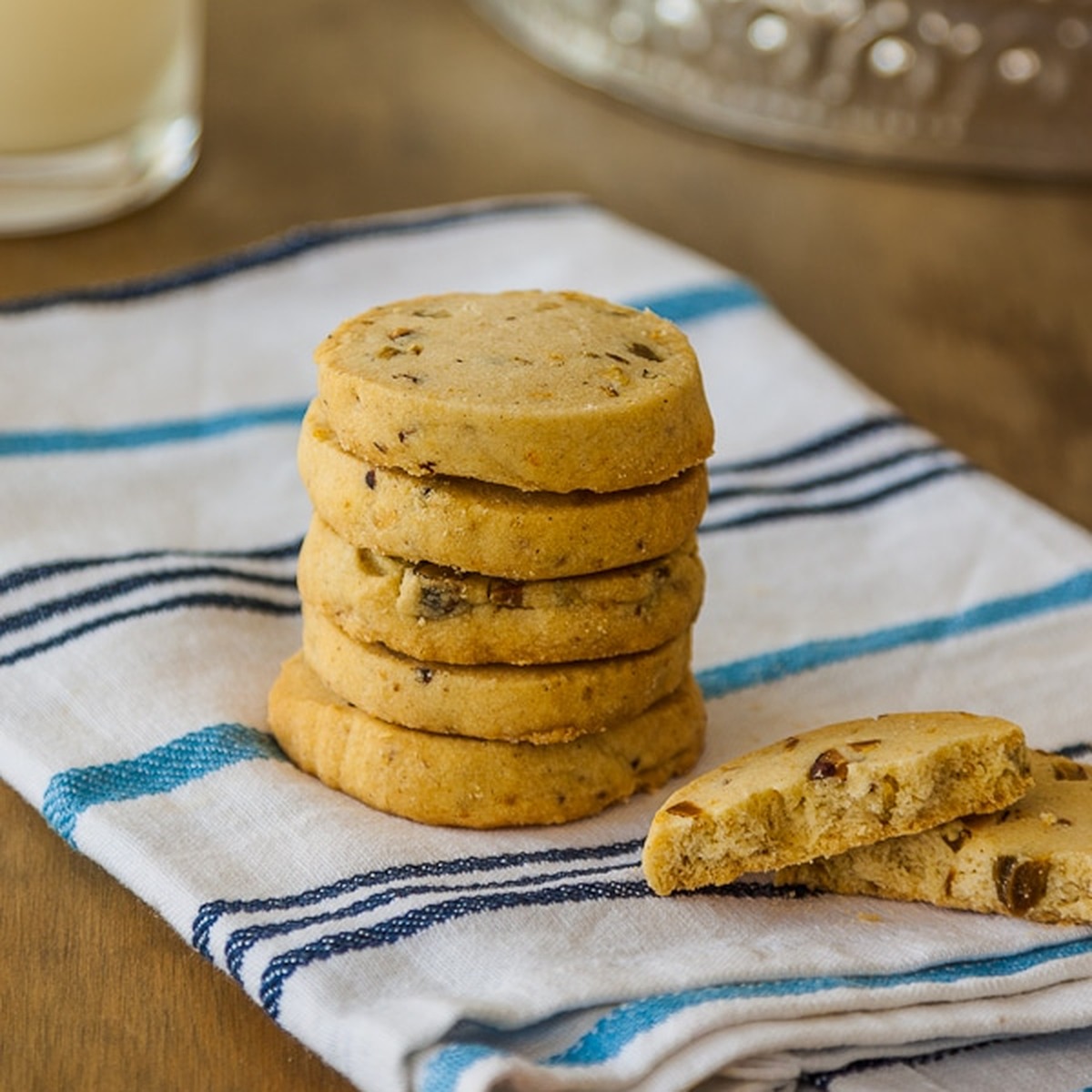Stack of cardamom cookies with lemon and pistachios on a blue striped kitchen towel