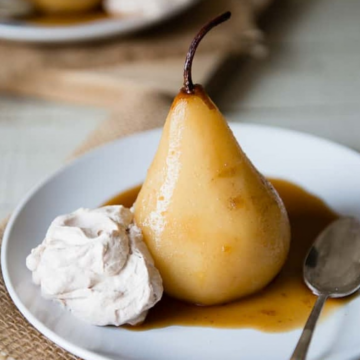 Chai poached pear with cinnamon whipped cream on a white plate
